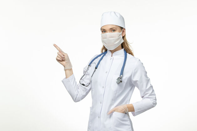 药品前视女医生身穿医疗服戴口罩因冠状病毒上桌淡白色疾病冠状病毒-大流行性疾病灯光医院佩戴