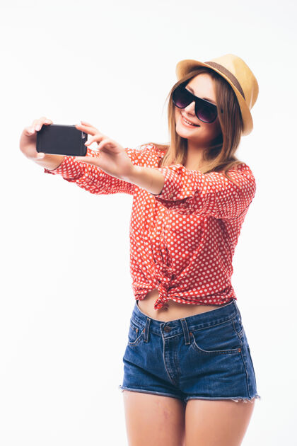 脸一个微笑的可爱女人在智能手机上自拍的照片 白色背景上的隔离美丽女性手机
