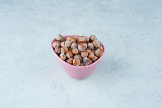 可口在大理石背景上放满坚果的粉红色小盘高质量照片粉色健康盘子