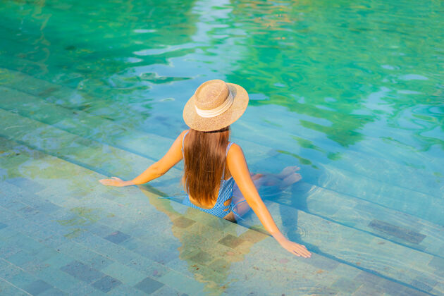 身体肖像美丽的亚洲年轻女子放松微笑享受休闲围绕游泳池近海边度假海景放松水疗乐趣