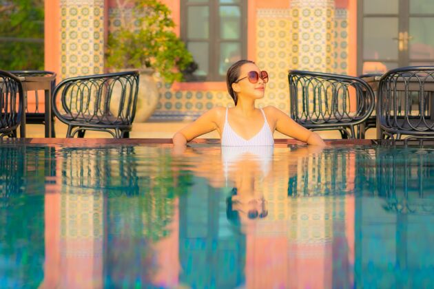 晒黑肖像美丽的亚洲年轻女子放松微笑在度假酒店游泳池周围享受休闲度假海滩热带活动