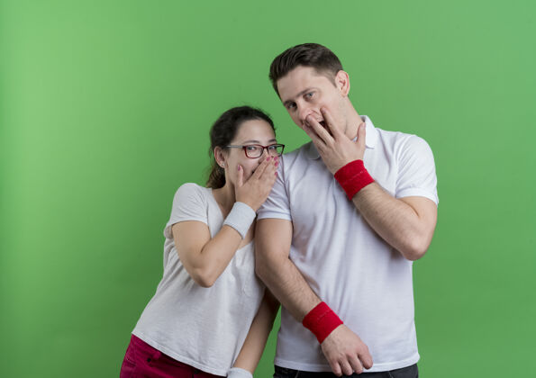 封面一对年轻的运动情侣双手捂着嘴站在绿色的墙壁上震惊不已女人看运动