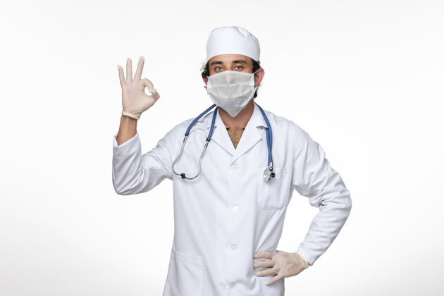 专业正面图身穿医疗服的男医生戴着口罩 以防白墙病毒传染医疗冠状病毒视图
