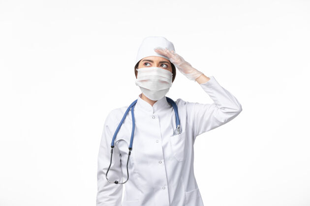 套装正面图女医生穿着白色无菌医疗服 戴着口罩 因柯维德病毒在白墙上冒充疾病病毒柯维德大流行疾病到期正面视图