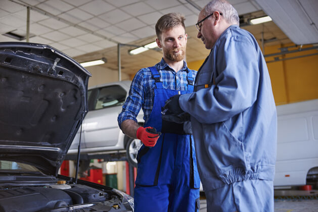 成年男子修理工在车间里修理汽车机械复印空间发动机