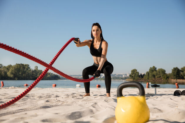 空气年轻健康的女人在沙滩上用绳子锻炼身体阳刚单独健身