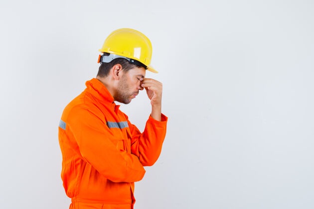 建筑师建筑工人穿着制服揉眼睛和鼻子 戴着头盔 看上去很累防护摩擦计划