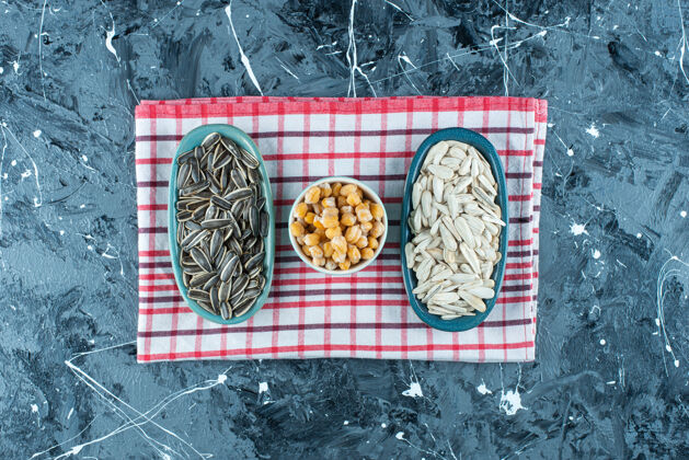 美味鹰嘴豆和葵花籽放在碗里 茶巾放在蓝色的上面顶视图茶毛巾美味
