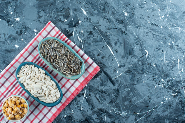 碗鹰嘴豆和葵花籽放在碗里 茶巾放在蓝色的上面茶毛巾顶视图种子