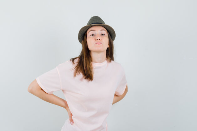 帽子穿着粉色t恤 戴着帽子 看上去精疲力竭 背痛的年轻女性 正面视图背痛黑发青春
