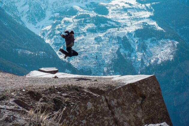 霜冻美丽的风景一个女人跳上了一个在喀尔巴点的岩石山顶自然凉爽下雪