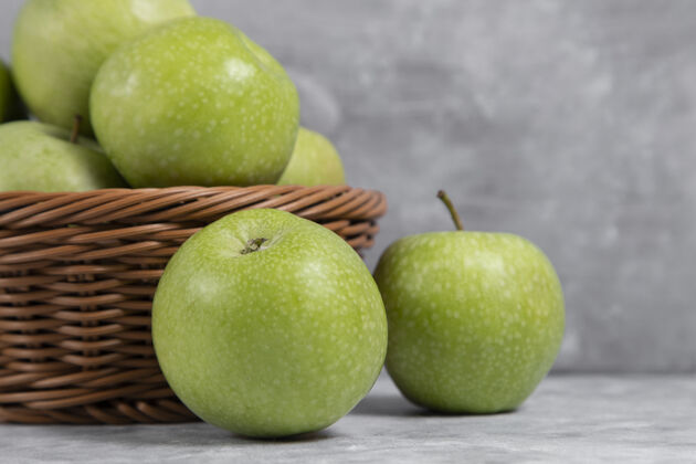 美味一篮柳条装的新鲜青苹果放在石头上植物水果苹果