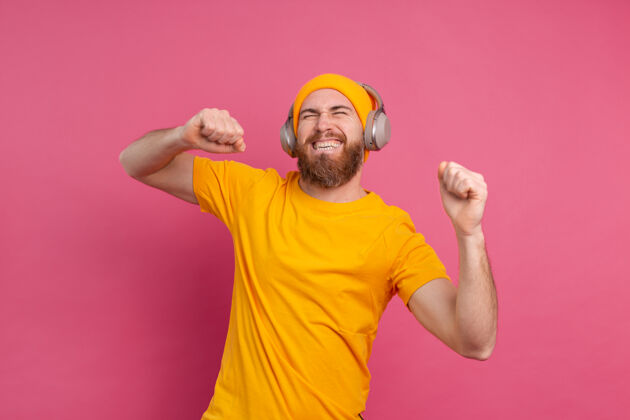 耳机帅哥带着粉色背景上的耳机随意跳舞表情男性娱乐