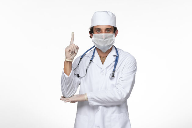 大流行正面图穿着医疗服的男医生 戴着无菌口罩 以防白墙病毒感染冠状病毒疾病穿着