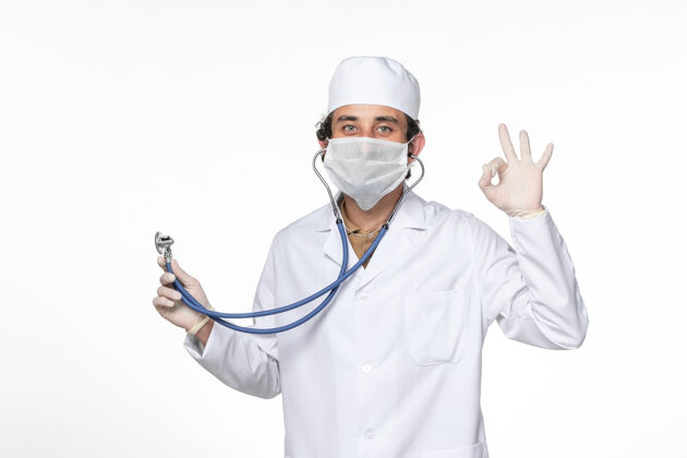 男性正面图：男医生 穿着医疗服 戴着口罩 用听诊器防止冠状病毒大流行医生大流行喷溅