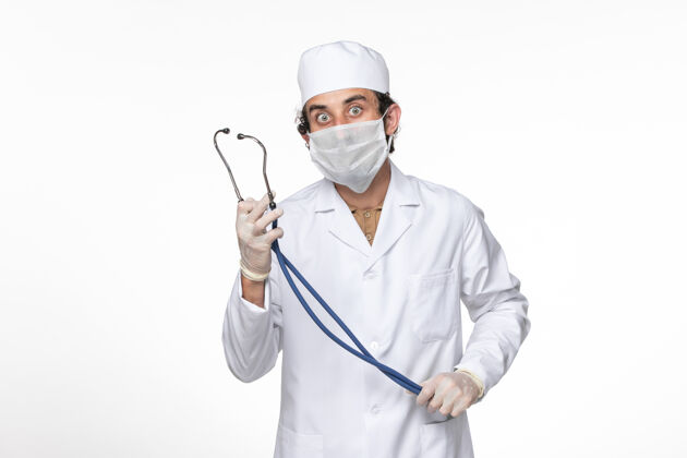 实验室外套正面图：男医生穿着医疗服 戴着口罩 以防白色桌面病毒喷溅冠状病毒大流行时戴着冠状病毒听诊器医疗听诊器防护