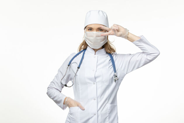 疾病正面图女医生穿着医疗服戴着口罩和手套因白墙上冠状病毒病病毒冠状病毒病病毒女比赛