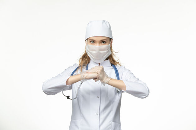 医疗正面图女医生穿着医疗服带着无菌口罩因白墙上冠状病毒病大流行健康工作大流行护士