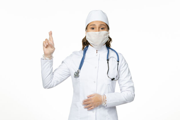 大流行正面图女医生身穿白色医疗服戴口罩因冠状病毒在白墙上大流行疾病隔离到期视图居家