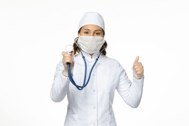医院正面图女医生穿着白色医疗服 戴着口罩在白墙上用听诊器给潘多米病毒治病听诊器护士专业