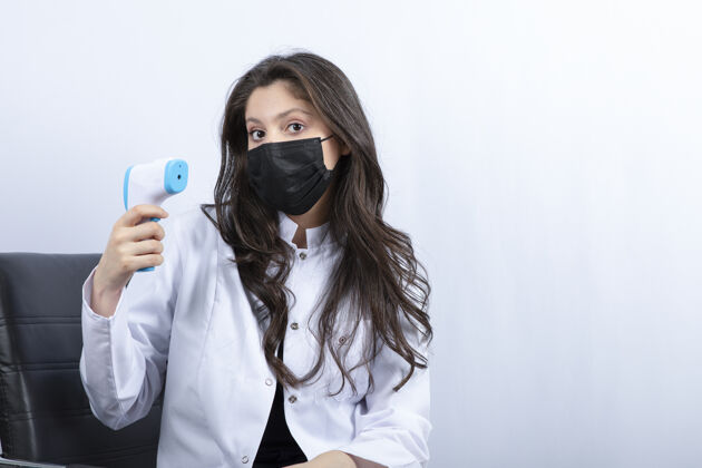 年轻女医生戴着医用口罩拿着体温计看前面疫苗口罩检查