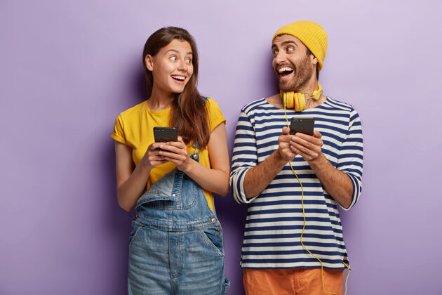 年轻快乐的男女朋友笑着看着对方 拿着手机情感信息紫色