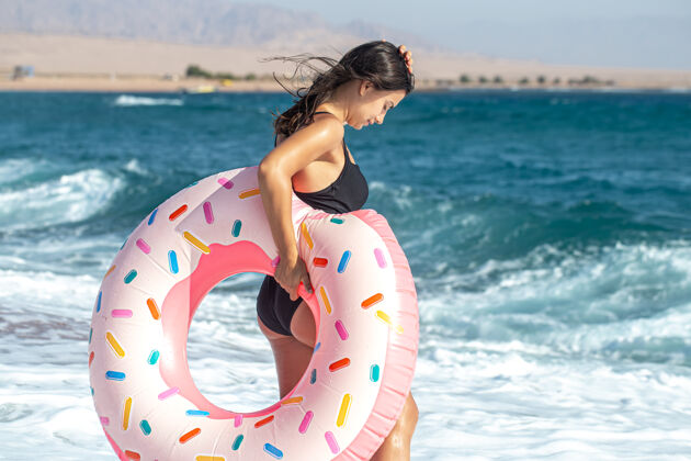 休息一个带着甜甜圈的女孩在海边游泳度假休闲娱乐的概念海浪大海女人