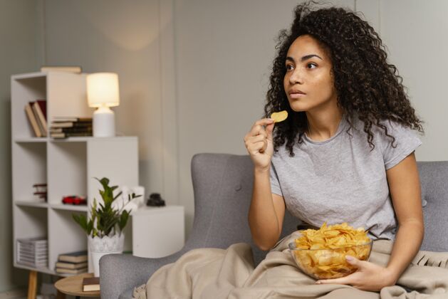 薯条坐在沙发上看电视吃薯片的女人吃饭看电视房子