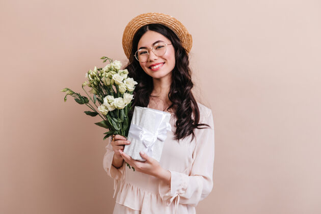 摄影棚拍摄摄影棚拍摄的白花日本女子迷人的亚洲模特手持桔梗花束和礼物幸福卷发微笑