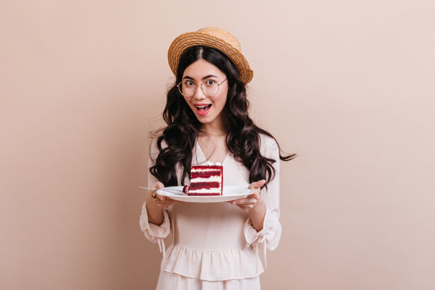 人高兴的亚洲女人拿着盘子和蛋糕草帽中国女人的摄影棚拍摄美味亚洲积极