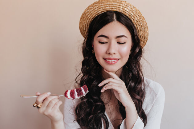 切片微笑浪漫的亚洲女人在吃蛋糕优雅的卷发女人在享受甜点摄影棚拍摄美味表情