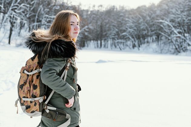 自然冬天背着背包的女人侧视图冬天全景女人