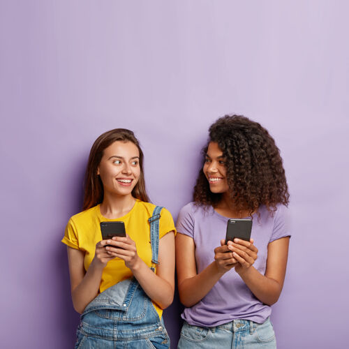 女人两个可爱的千禧一代女孩用手机女孩聊天朋友