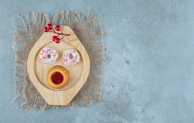 甜点甜甜圈和果冻蛋糕放在大理石背景的木制盘子上高质量的照片美味蛋糕烘焙食品