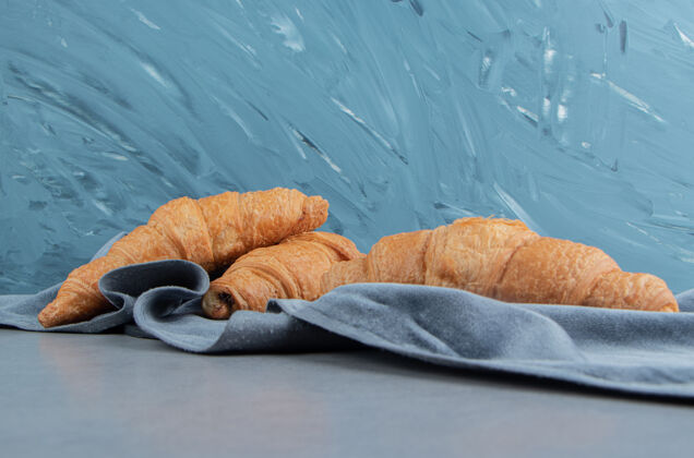 美味美味的牛角面包在毛巾上 在蓝色的背景上高品质的照片美味巧克力糖