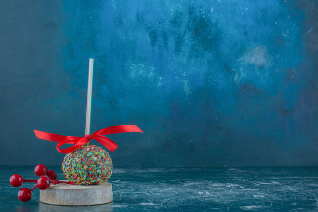 圣诞节一个糖果涂层棒棒糖和圣诞浆果装饰一块木头上的蓝色背景高品质的照片节日糖果浆果