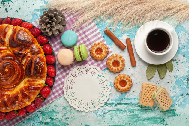 饼干蓝色桌子上的草莓派配饼干 法式马卡龙和一杯茶杯子糖食物