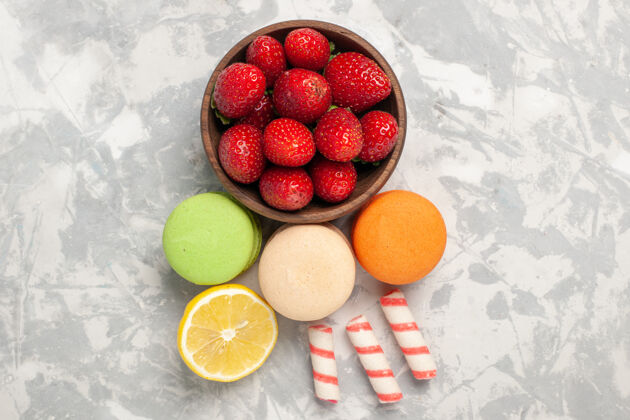 法国顶视图法国马卡龙与新鲜的红色草莓在白色表面生的水果饼干
