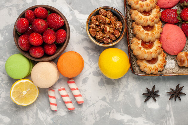 饼干顶视图法国马卡龙与新鲜的红色草莓和饼干的白色表面饼干顶部甜食