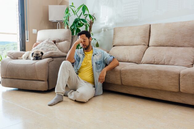 放松一个男人坐在家里的地板上带着疲惫的表情水平拍摄生活看欢乐