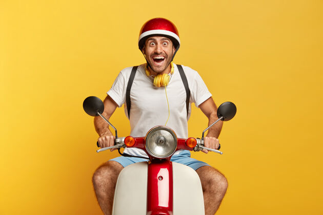 自行车兴奋快乐的帅哥司机骑着红色头盔的滑板车耳机朋友速度