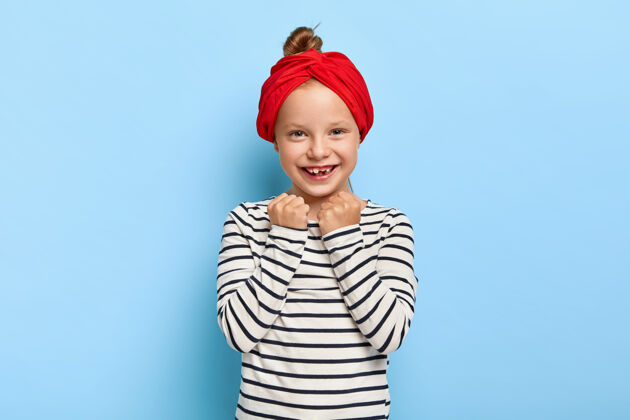 玩摄影棚拍摄的美丽时尚的小女孩与红色头带摆姿势围巾室内童年