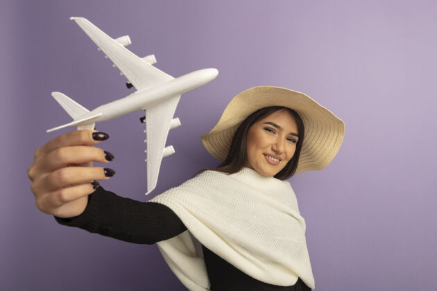 女人戴着白色围巾 戴着夏帽的年轻女子展示着玩具飞机欢快的笑容飞机玩具表演