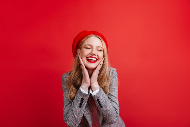 发型漂亮的法国女孩在红墙上摆姿势高兴的金发女郎微笑着微笑成人年轻人