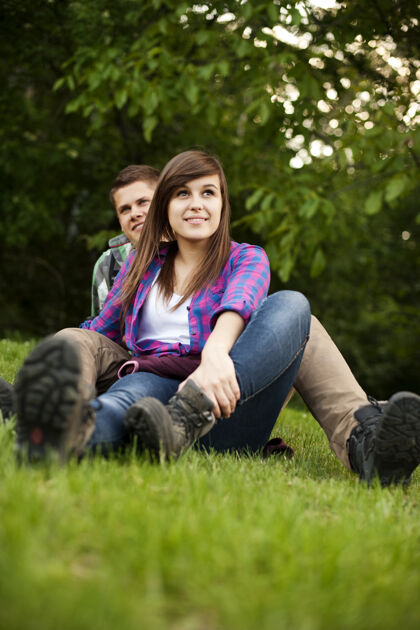 鞋子坐在空地上的年轻夫妇草地徒步旅行旅游