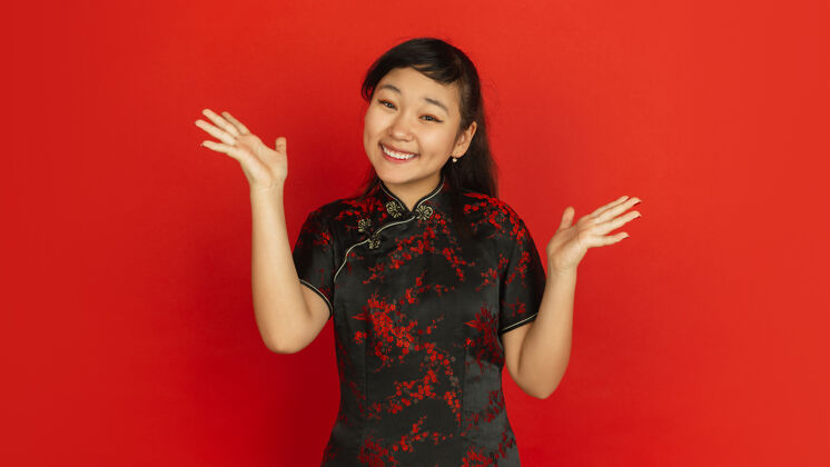 红色手势 微笑 邀请中国新年快乐红色背景上的亚洲少女肖像穿着传统服装的女模特看起来很快乐庆祝 人类情感复制空间欢乐庆祝普通话