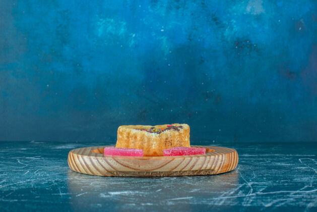 蛋糕一个小蛋糕和一个蓝色背景的木制盘子上的Marmeldes高品质的照片糖美味口感