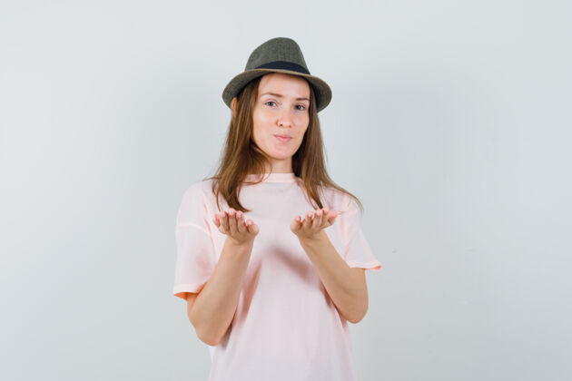 手掌穿着粉色t恤的年轻女孩 戴着帽子假装手掌上拿着什么东西 前视图孩子随意可爱