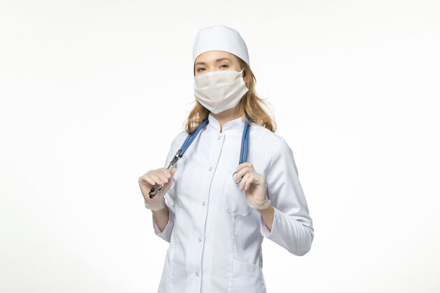 冠状病毒正面图年轻女医生穿着医疗服戴着防护面罩 白色办公桌上有冠状病毒正面医生面罩