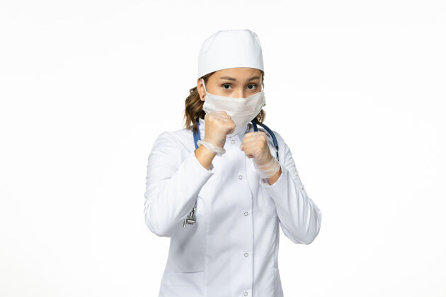 电话正面图年轻女医生戴着无菌口罩和手套 由于冠状病毒在浅白的表面手套耳机正面